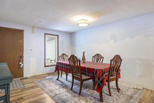 dining room with wood-type flooring and a textured ceiling