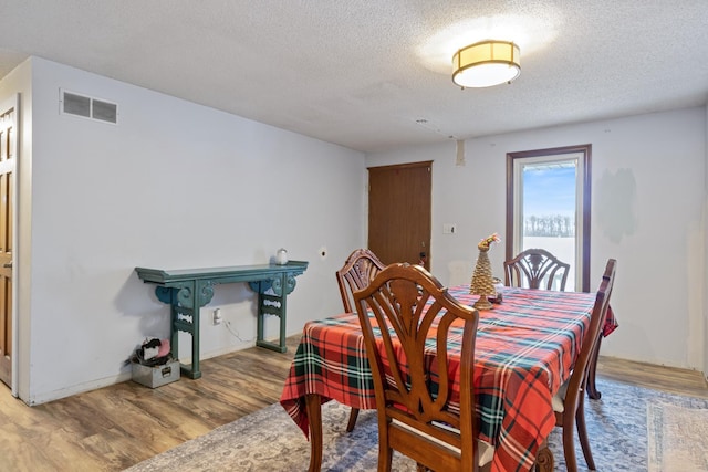 dining space featuring a textured ceiling and light wood-type flooring