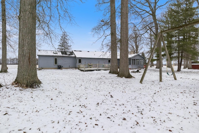 snow covered back of property featuring a deck