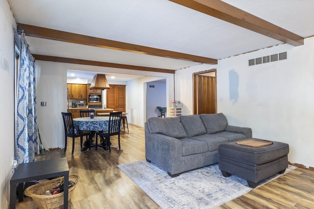 living room featuring beamed ceiling and wood-type flooring