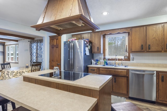 kitchen featuring sink, appliances with stainless steel finishes, a center island, island range hood, and a textured ceiling