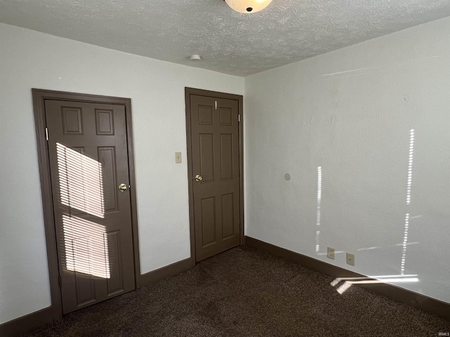 empty room featuring dark colored carpet and a textured ceiling