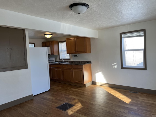 kitchen featuring white refrigerator, plenty of natural light, dark wood-type flooring, and sink