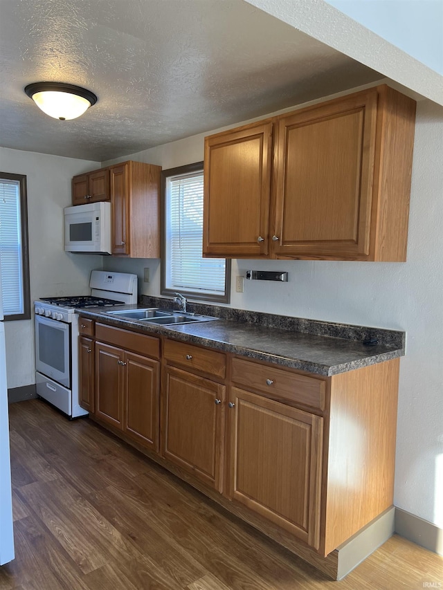 kitchen featuring white appliances, dark hardwood / wood-style flooring, sink, and a textured ceiling