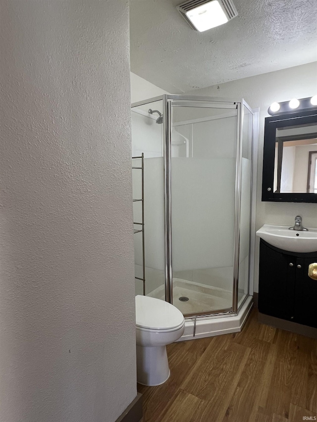 bathroom featuring vanity, hardwood / wood-style flooring, a shower with door, and a textured ceiling