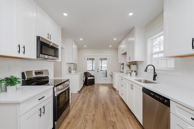 kitchen featuring a healthy amount of sunlight, appliances with stainless steel finishes, sink, and white cabinets