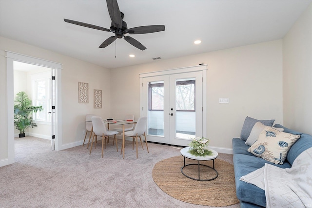 carpeted living room with french doors and ceiling fan