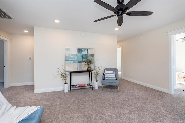 living area featuring light carpet and ceiling fan