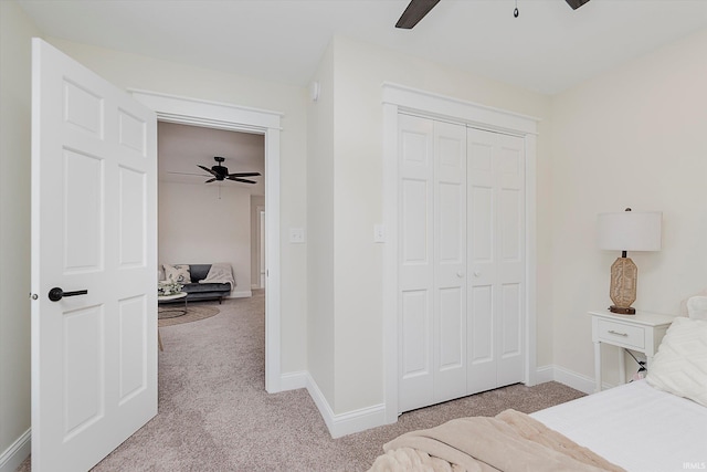 bedroom with light colored carpet, ceiling fan, and a closet