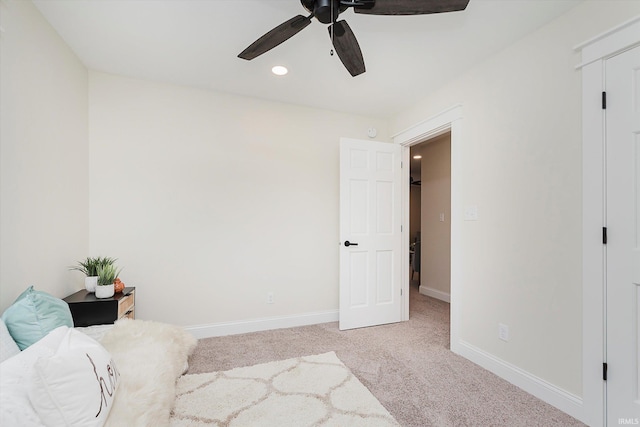 living area featuring light carpet and ceiling fan