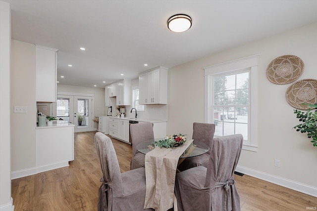 dining room with french doors, sink, and light hardwood / wood-style flooring