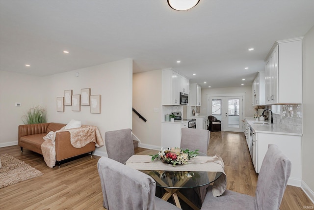 dining room with sink, light hardwood / wood-style flooring, and french doors