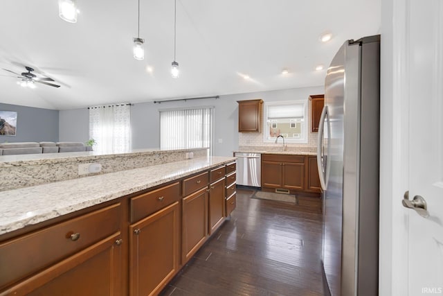 kitchen featuring backsplash, plenty of natural light, stainless steel appliances, light stone countertops, and decorative light fixtures