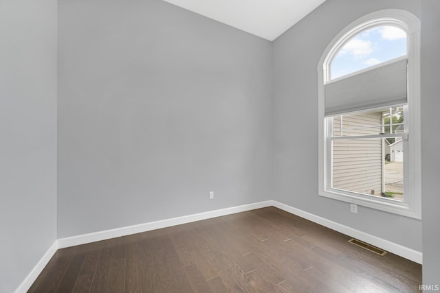 unfurnished room featuring lofted ceiling and dark hardwood / wood-style flooring