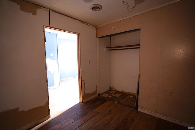 unfurnished bedroom with dark wood-type flooring and a closet