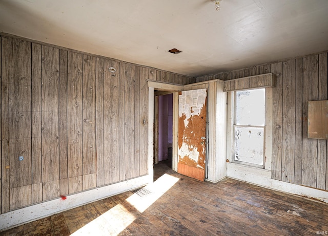 empty room featuring dark wood-type flooring and wood walls