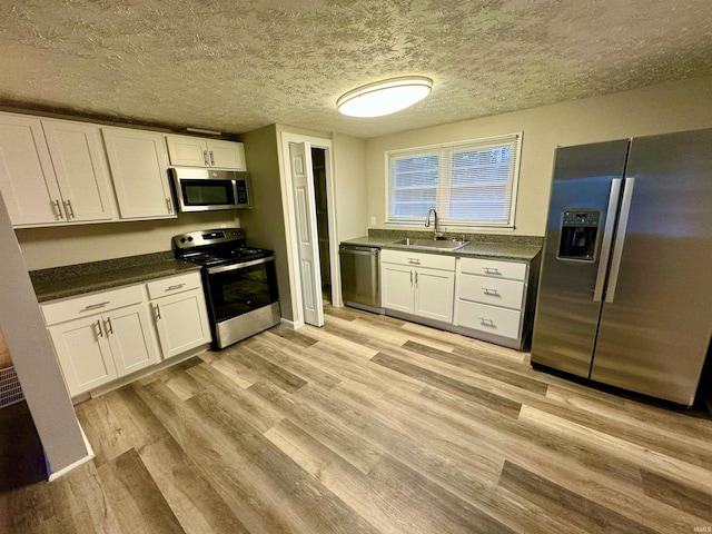 kitchen with appliances with stainless steel finishes, sink, and white cabinets