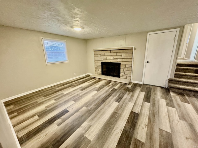 unfurnished living room featuring wood-type flooring, a fireplace, and a textured ceiling