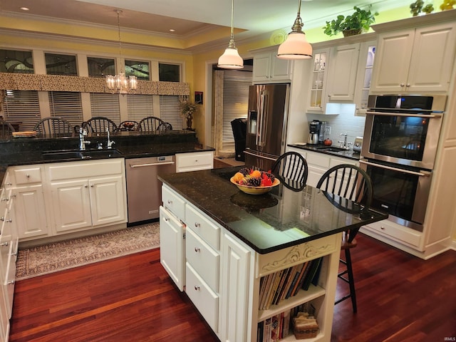 kitchen with sink, a breakfast bar area, decorative light fixtures, appliances with stainless steel finishes, and a kitchen island