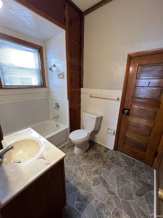 bathroom featuring vanity, toilet, tile walls, and a tub