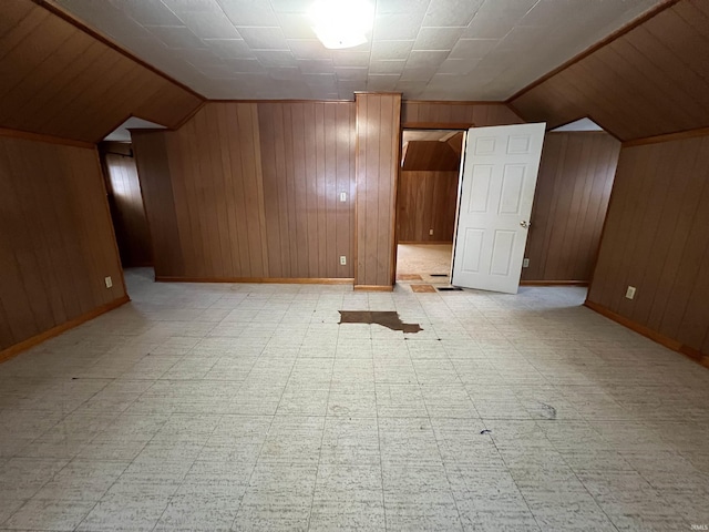 additional living space featuring lofted ceiling and wood walls