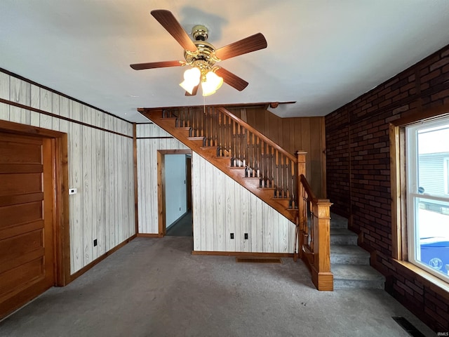 stairway featuring ceiling fan, brick wall, and wood walls