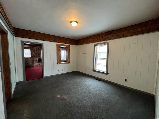 carpeted spare room with wood walls