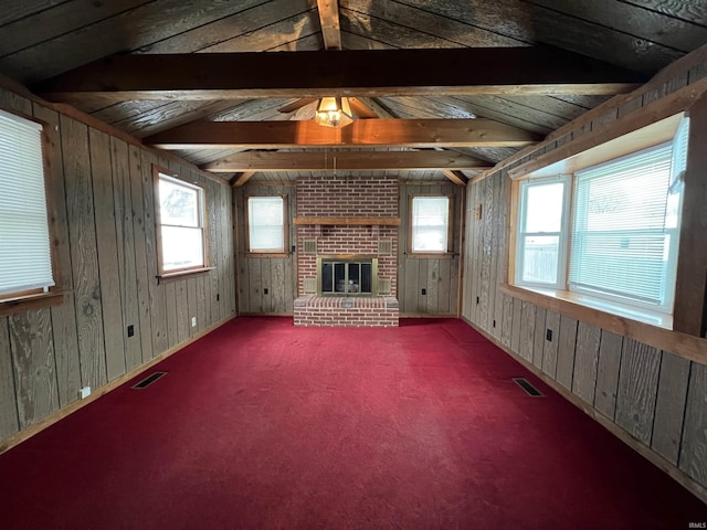 unfurnished living room with lofted ceiling with beams, a brick fireplace, and a healthy amount of sunlight