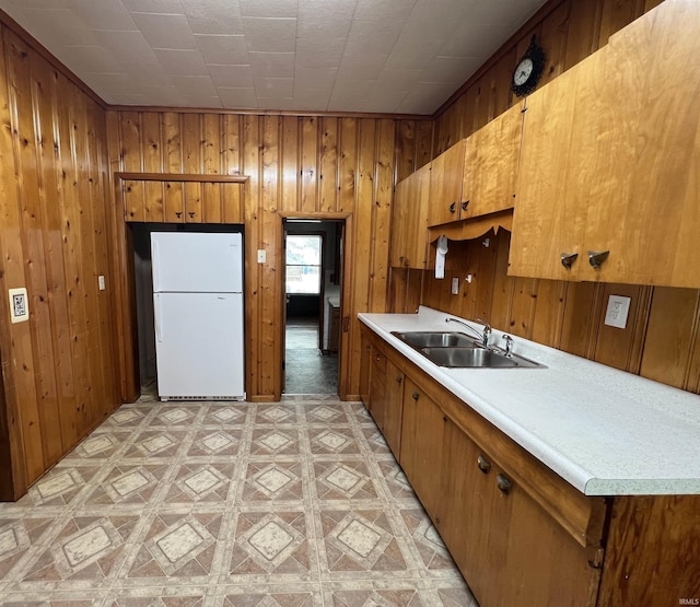 kitchen featuring sink, wood walls, and white refrigerator