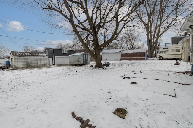 snowy yard featuring a storage shed