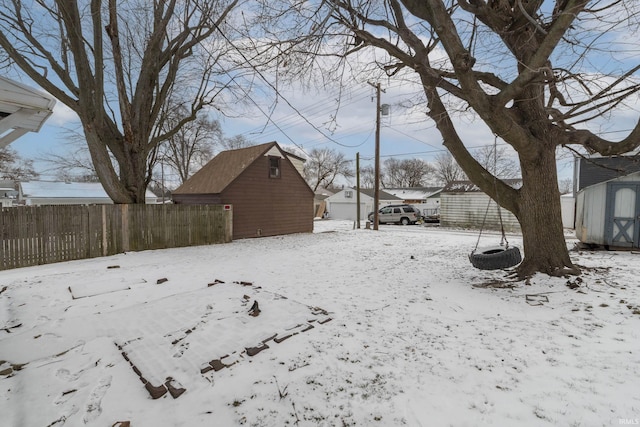 yard layered in snow featuring a shed