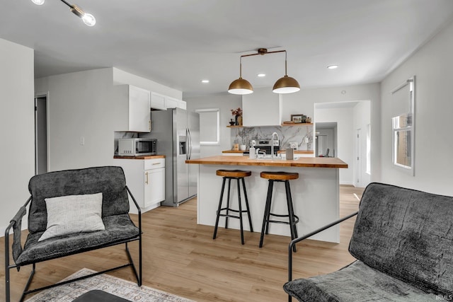 kitchen featuring pendant lighting, white cabinetry, wooden counters, and appliances with stainless steel finishes