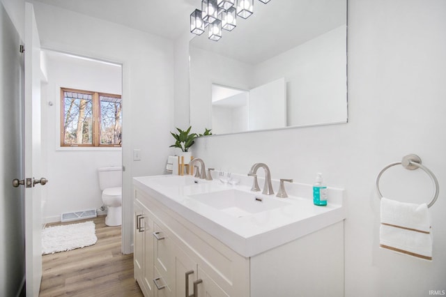 bathroom with hardwood / wood-style flooring, vanity, and toilet