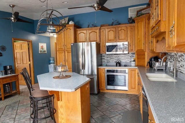 kitchen featuring sink, backsplash, a kitchen island, and appliances with stainless steel finishes