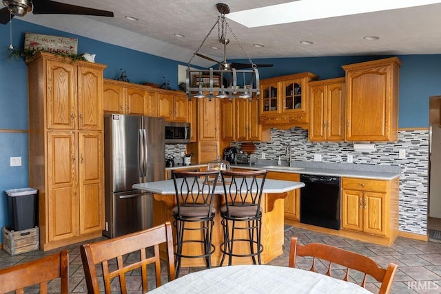 kitchen with appliances with stainless steel finishes, tasteful backsplash, lofted ceiling, sink, and a center island