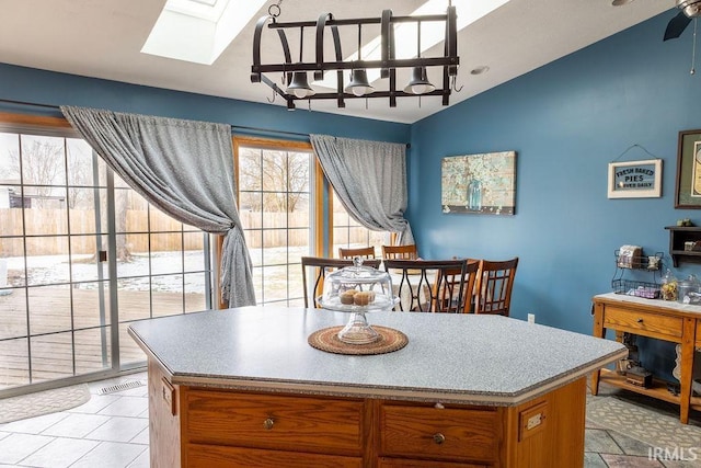 kitchen with ceiling fan, vaulted ceiling with skylight, and a kitchen island