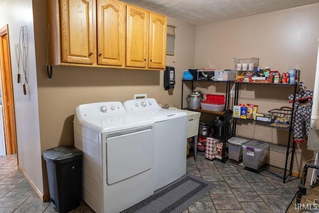 washroom with cabinets, washing machine and clothes dryer, and a textured ceiling