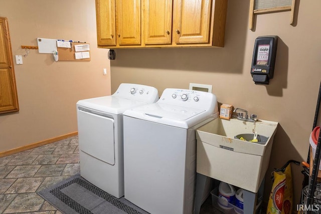 clothes washing area featuring sink, cabinets, and washing machine and clothes dryer