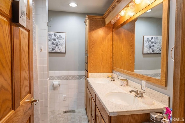 bathroom featuring vanity and tile walls