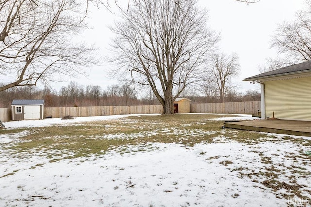 snowy yard featuring a wooden deck and a storage unit