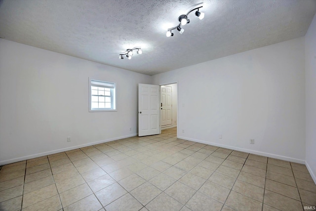 tiled empty room featuring a textured ceiling