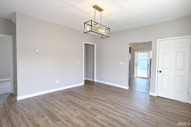 spare room with an inviting chandelier, dark hardwood / wood-style flooring, and a textured ceiling