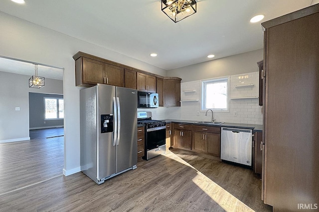 kitchen with appliances with stainless steel finishes, pendant lighting, sink, dark hardwood / wood-style flooring, and decorative backsplash