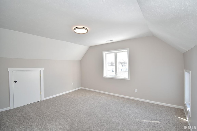 bonus room featuring vaulted ceiling, carpet, and a textured ceiling