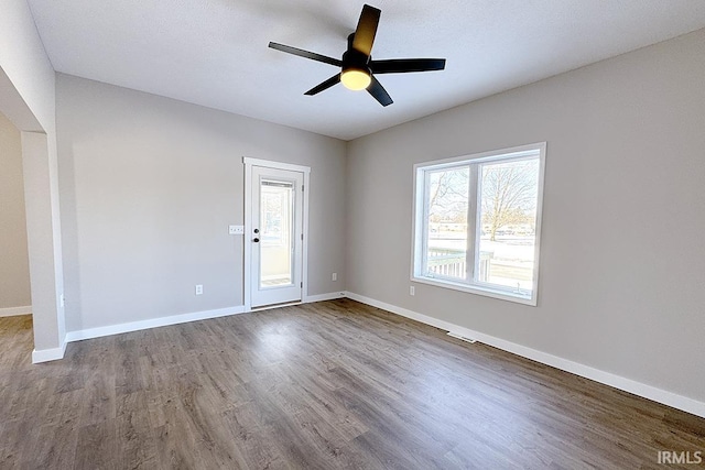 empty room featuring ceiling fan, hardwood / wood-style flooring, and a healthy amount of sunlight