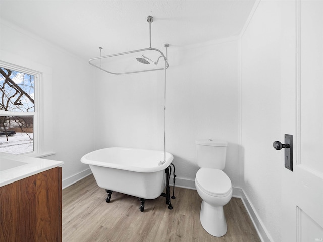 bathroom featuring ornamental molding, hardwood / wood-style floors, a bathtub, and toilet