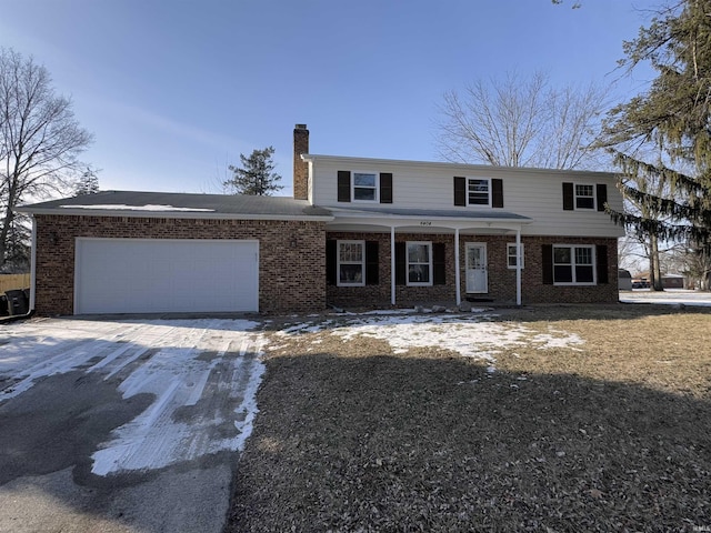 view of front of property featuring brick siding, driveway, a chimney, and an attached garage