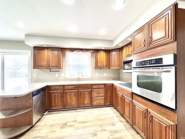 kitchen with brown cabinets, open shelves, stainless steel appliances, light wood-style flooring, and a peninsula