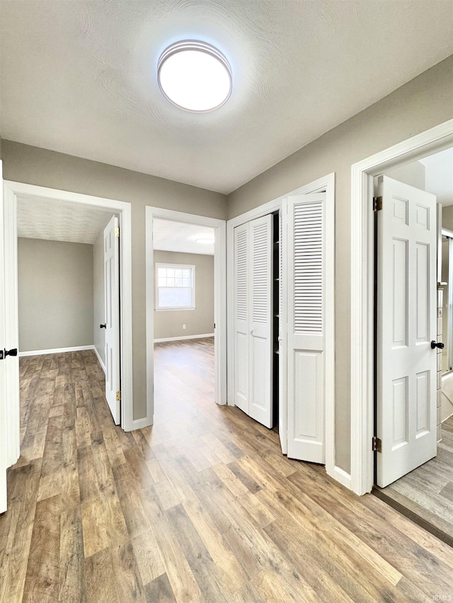 corridor featuring light wood-style flooring and baseboards