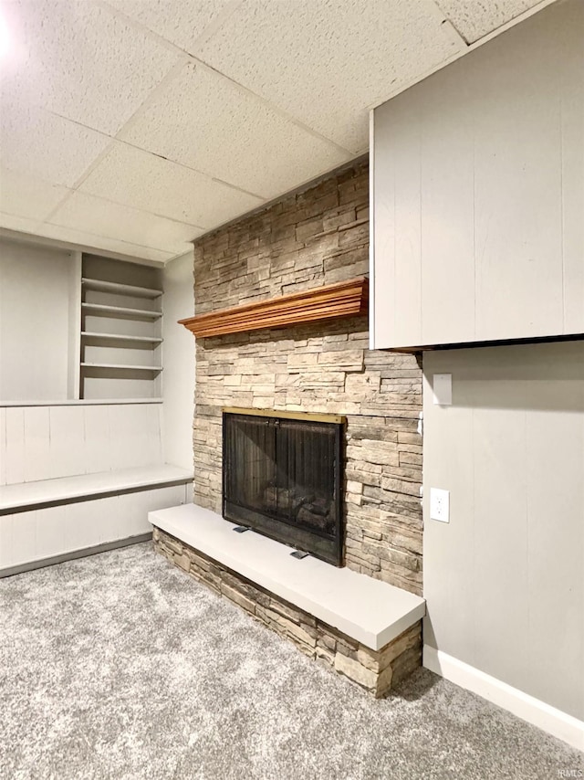 details with a stone fireplace, carpet flooring, a paneled ceiling, and baseboards